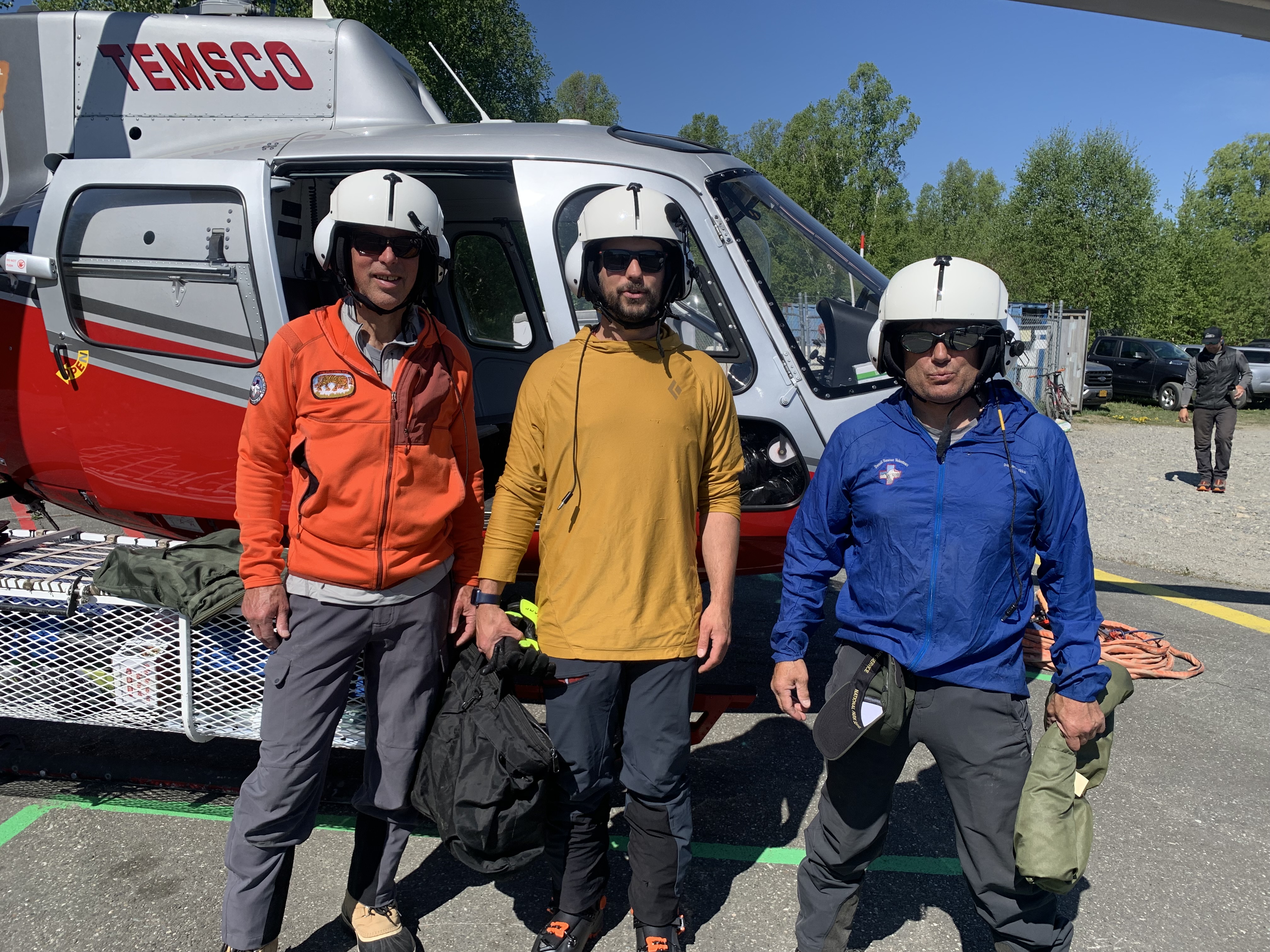Basecamp patrol #3 Three climbers stand outside the open door of a helicopter