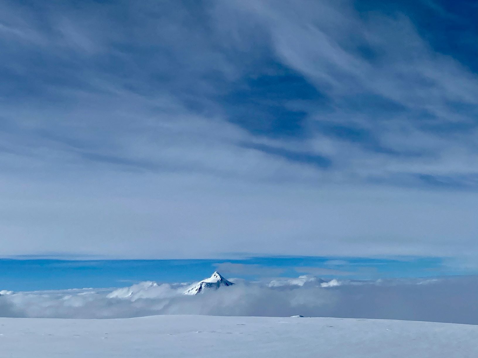 A mountain peak appears through layers of soft clouds