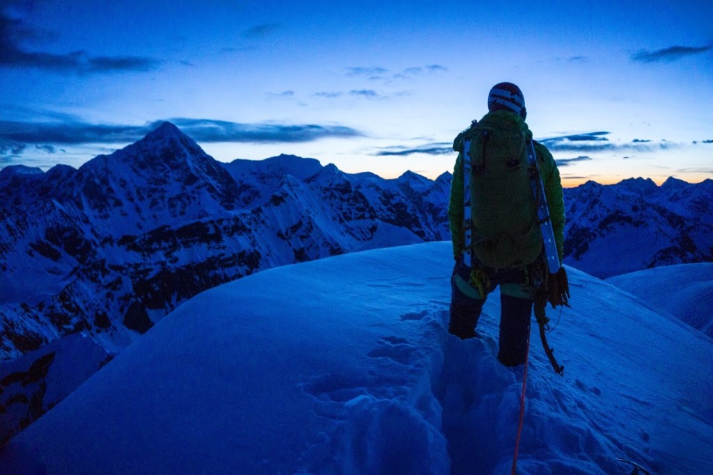 Mt. Katherine Summit Photo A climber on top of a snowy peak stares off into a distant sunset