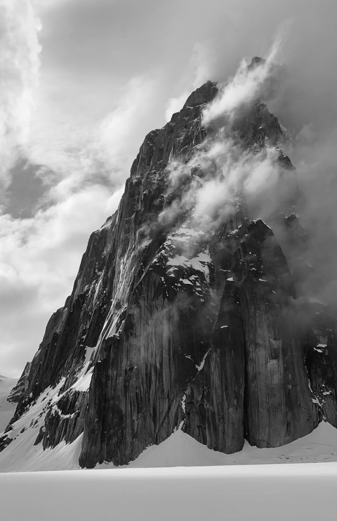 Mt. Dickey Between Storms Black and white image of a cloud-shrouded rocky peak