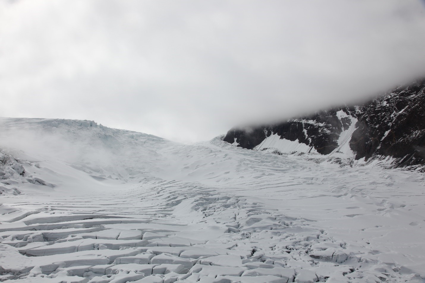 Severely crevassed glacier surface transitions to rocky ridge