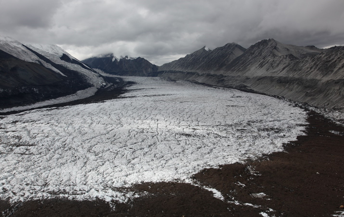 A high contrast black and white image of a glacier surface reveals a dramatically cracked and jumbled snow surface