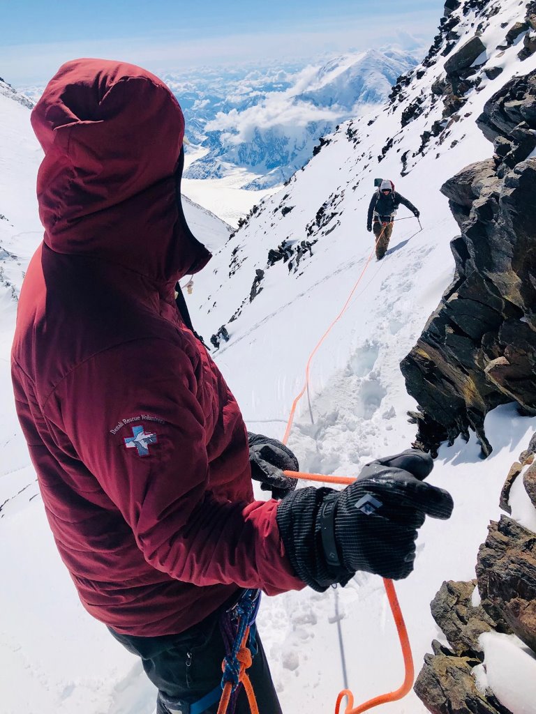 Climber belays his rope partner up a snowy ridge