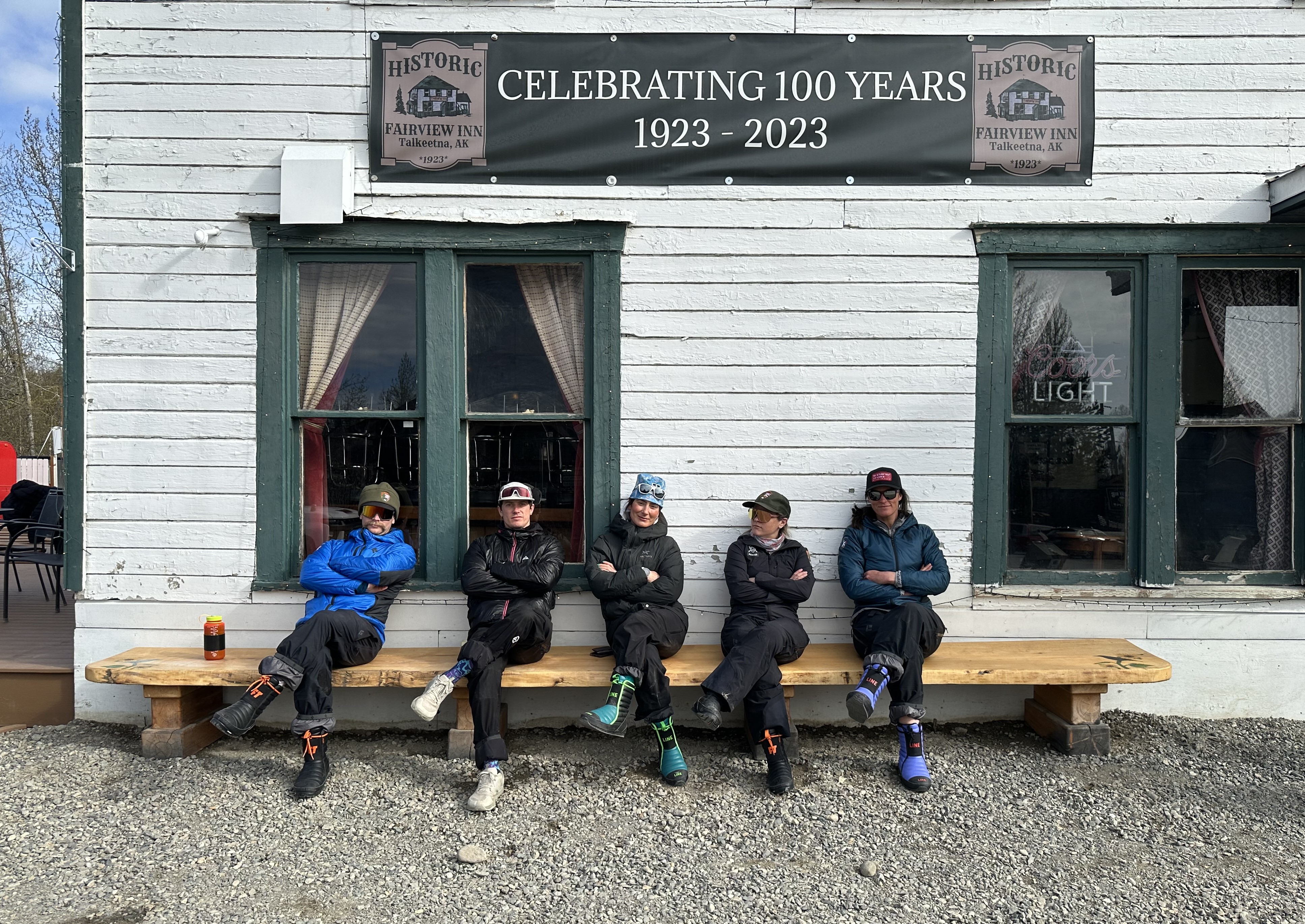 Five climbers sit on a bench with arms crossed and legs crossed
