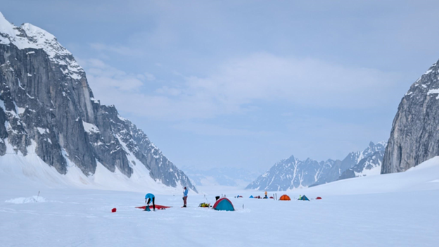 Camped on Pika Glacier Mountaineers and tents on a snowy field between to mountain peaks