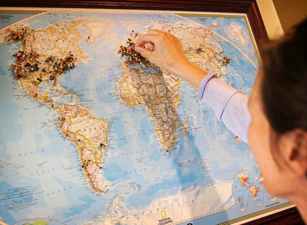 A woman places a brightly colored pin on a world map 