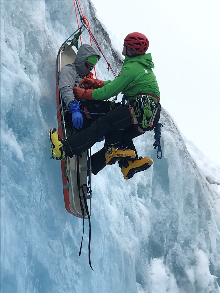 Rigging for Rescue Training A ranger secures an unresponsive patient to a rescue litter in steep, icy terrain