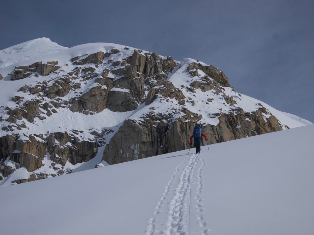 Ranger carrying big pack up a snow slope