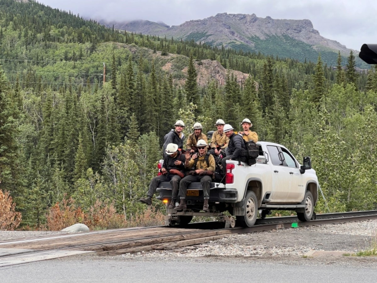 Riley Fire Update 7.12.24 - BLM Alaska Fire Service Photo Seven firefighters are transported along railroad tracks in the back of a pickup truck.