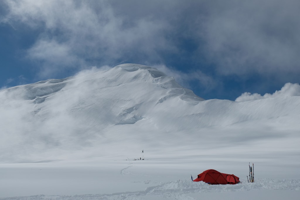 Photo courtesy of Scott Larson A lone tent in the foreground, Mount Capps in the background. NPS installing a weather antenna in the midground.