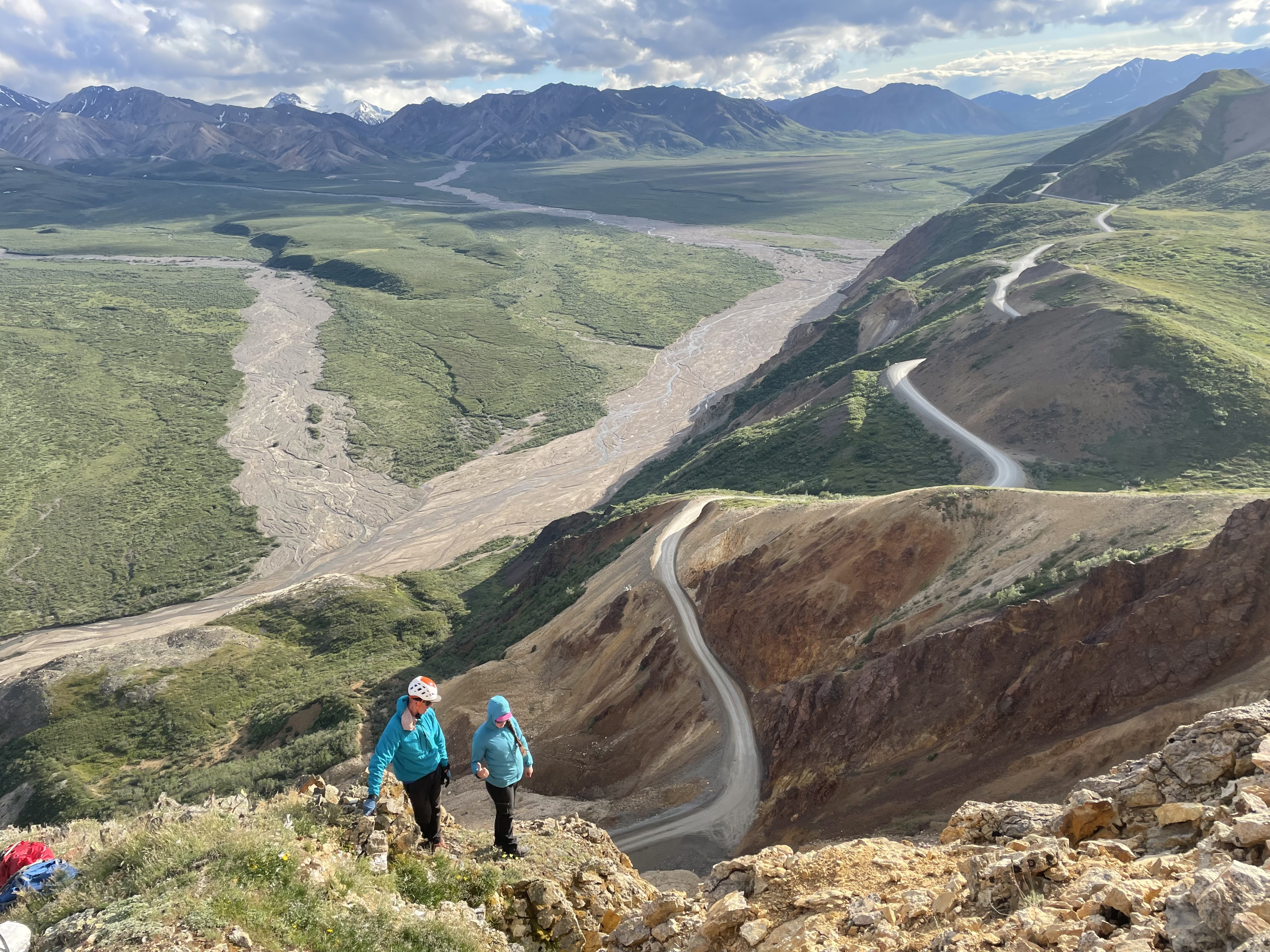 Discussing access points to the eagle's nest Two climbers have a conversation on a rocky ridge overlooking a vast braided river valley