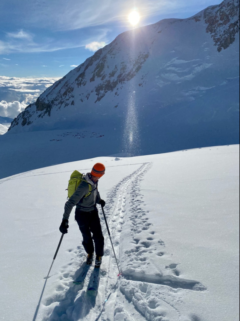SunSpectacle Ranger on skis looks behind him at a sparkly ray of sunshine