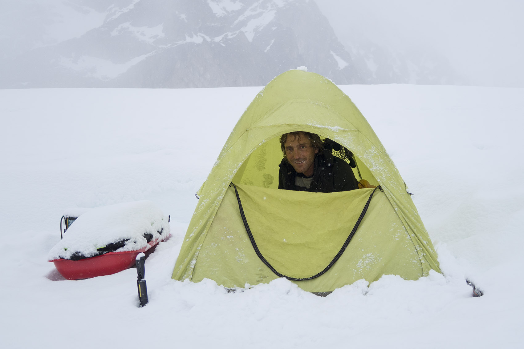 A tent-bound climber peers out his tent