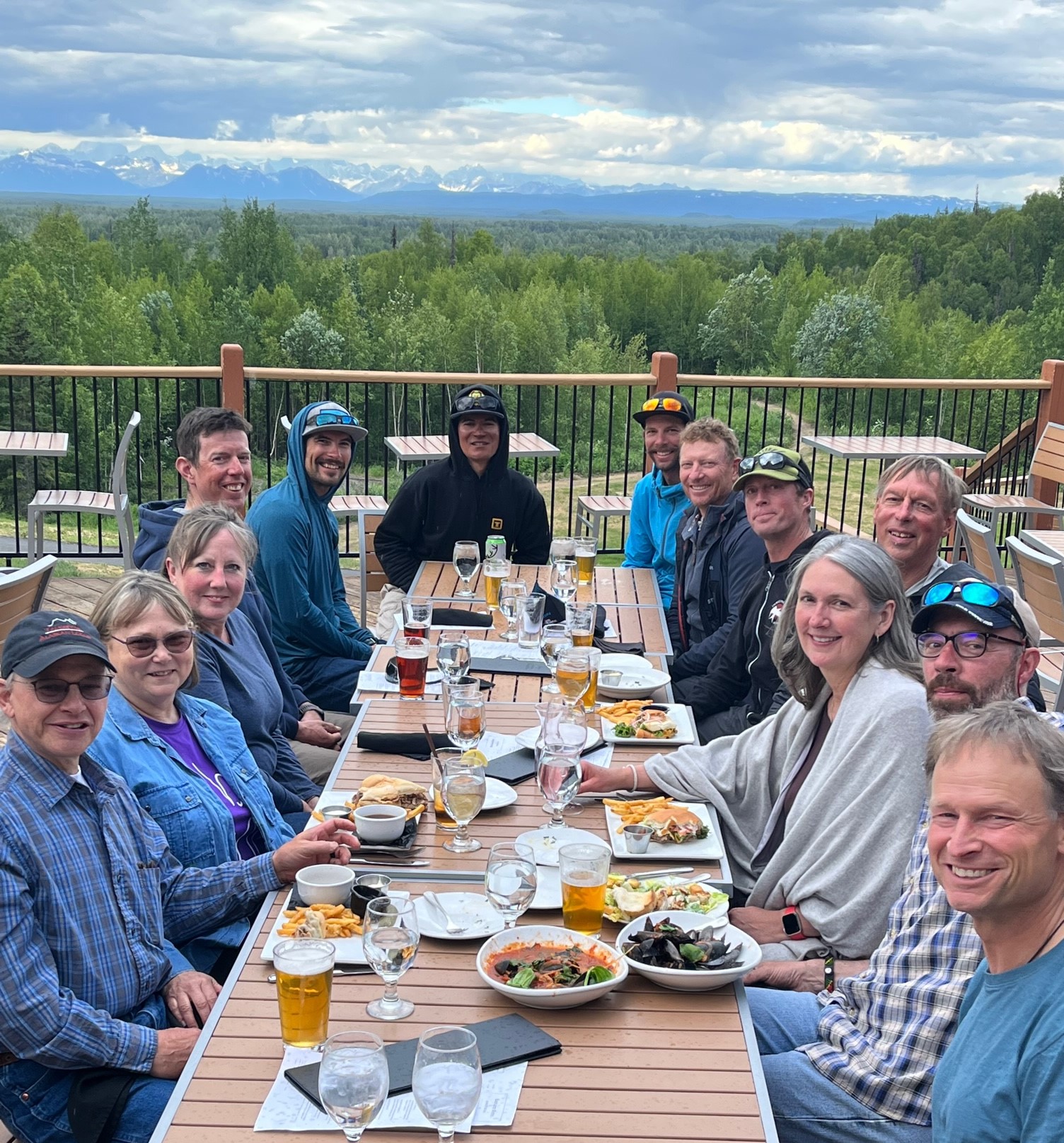 A table of smiling people at dine on an outdoor deck