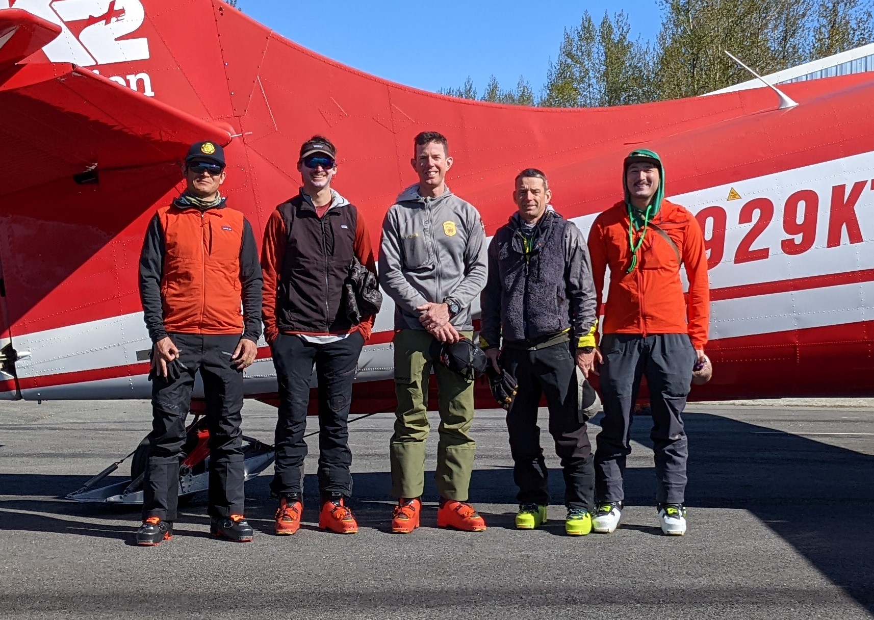 Five mountaineers stand in front of small airplane