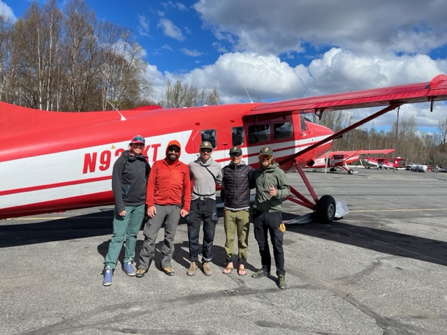 West Buttress Patrol #2 Five climbers stand outside a red and white airplane in street clothes