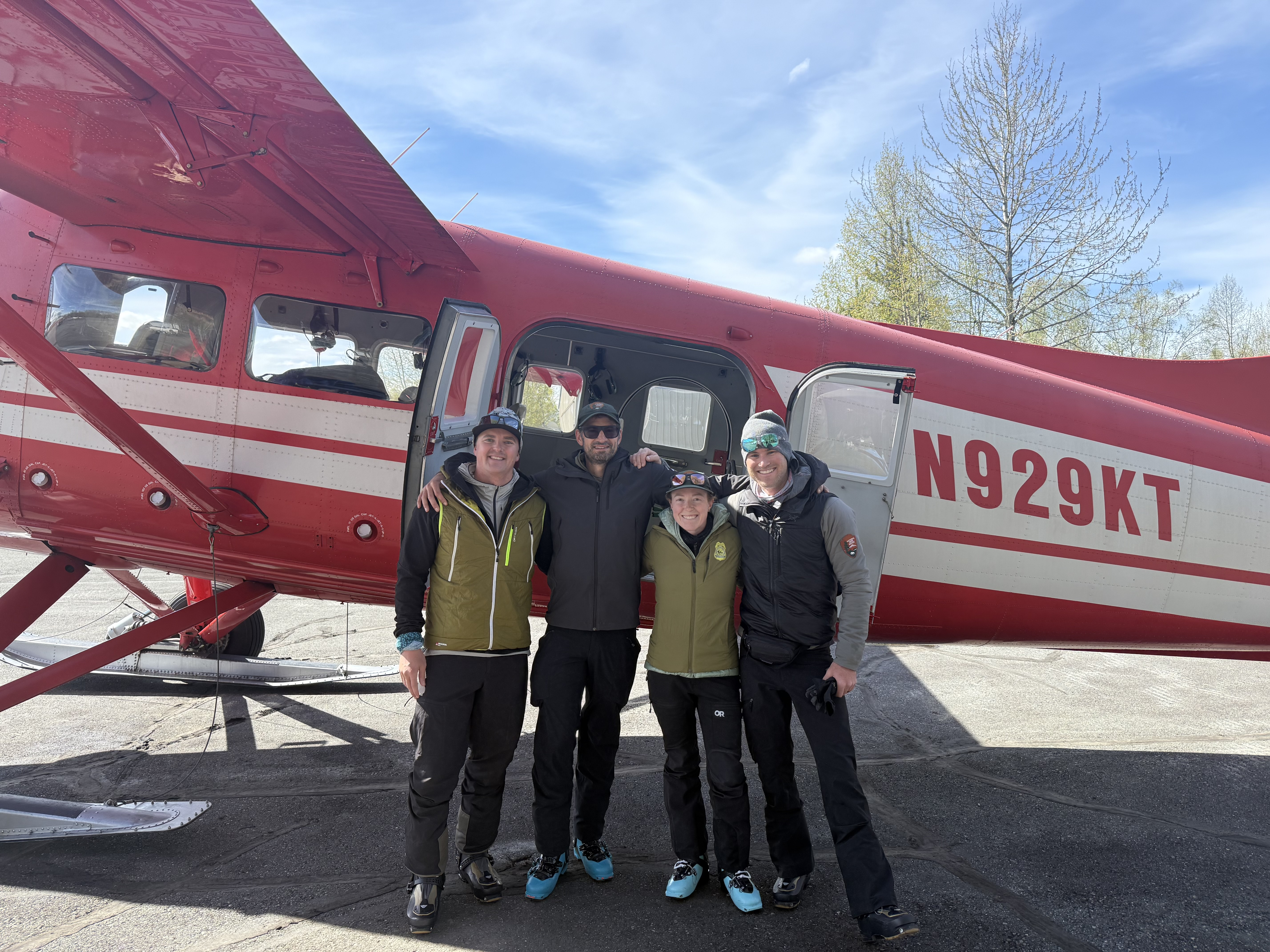 Four rangers stand arm in arm in front a red plane