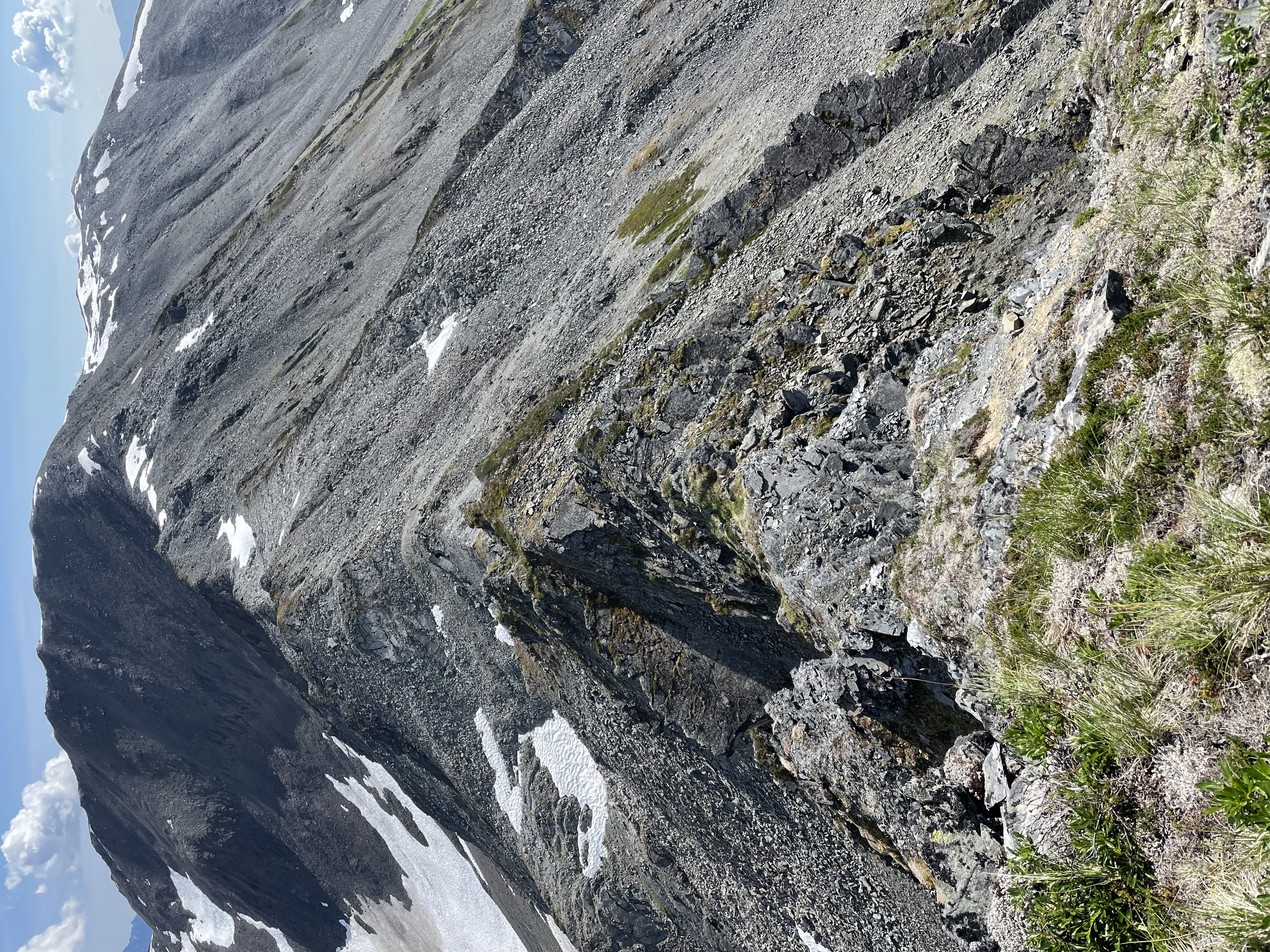 A steep, knife-edged ridgeline covered with scree and patches of snow.