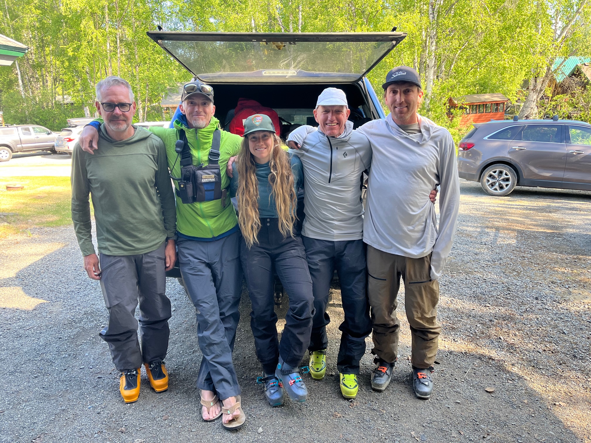 Weber 14K patrol Five smiling climbers sit on the back of a pickup truck filled with duffel bags