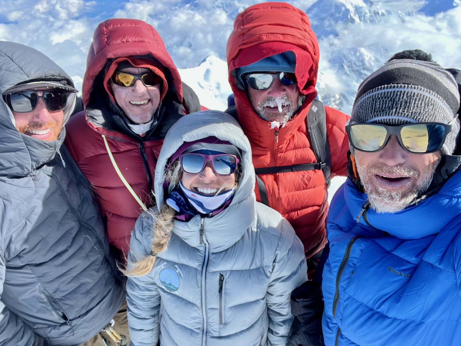 Big day Five well-bundled and frosty climbers smile take a selfie on the summit