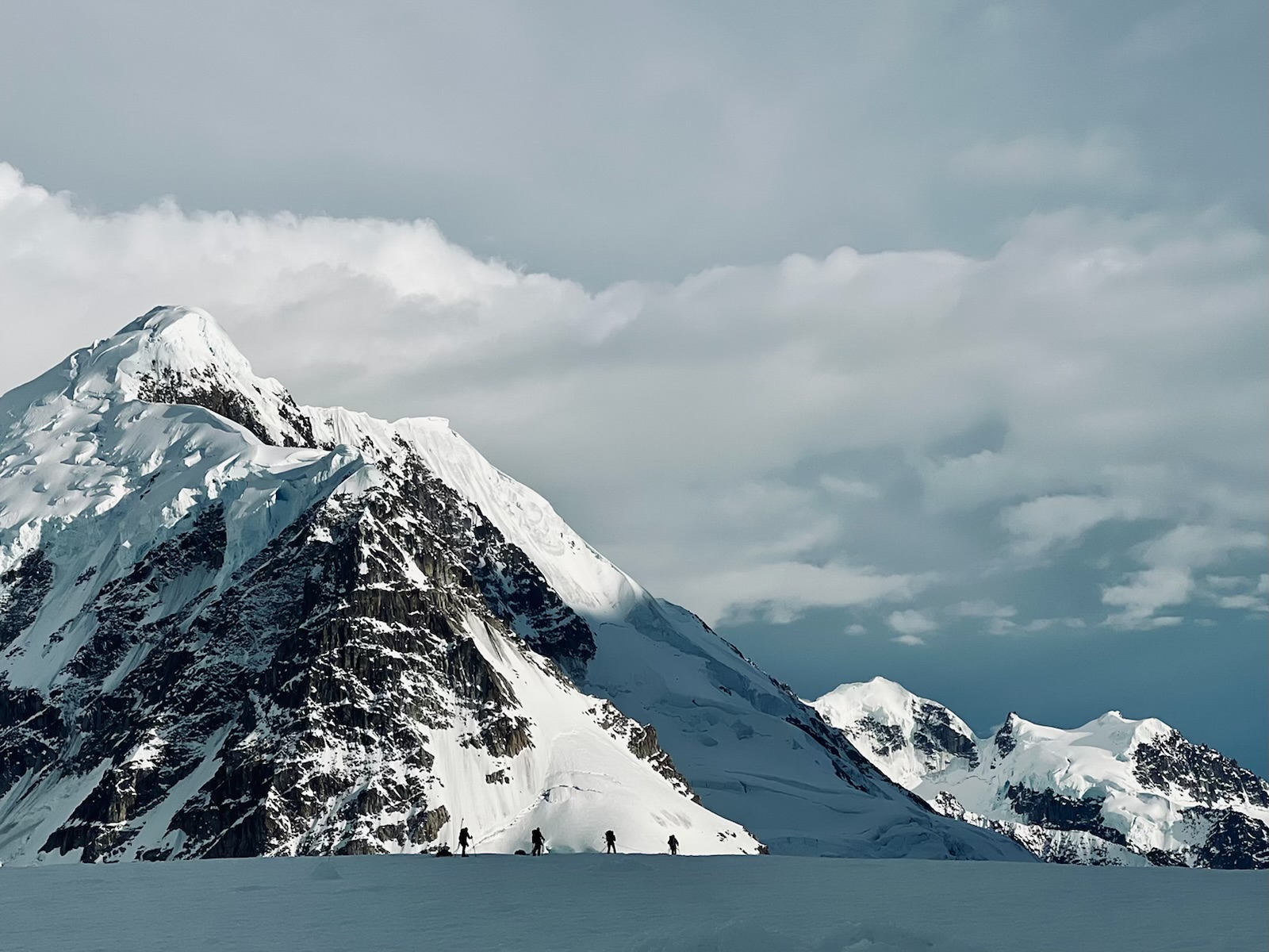 Silhouettes of four mountaineers contrasted in the snowy face of Mount Francis