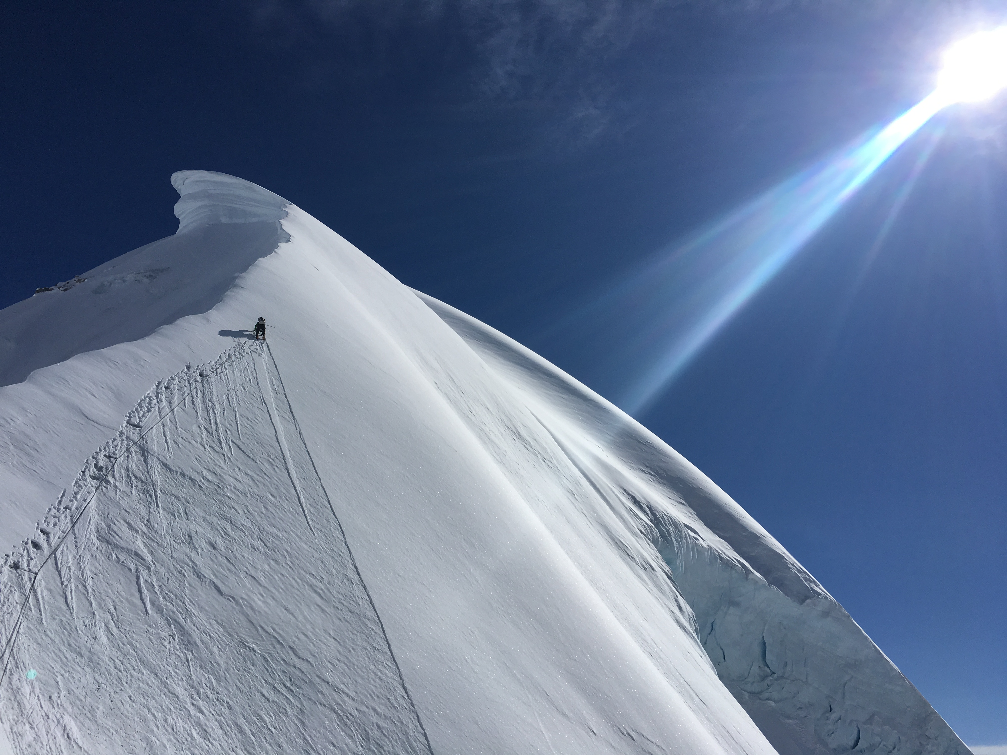 Climber ascends a steep, snowy ridge