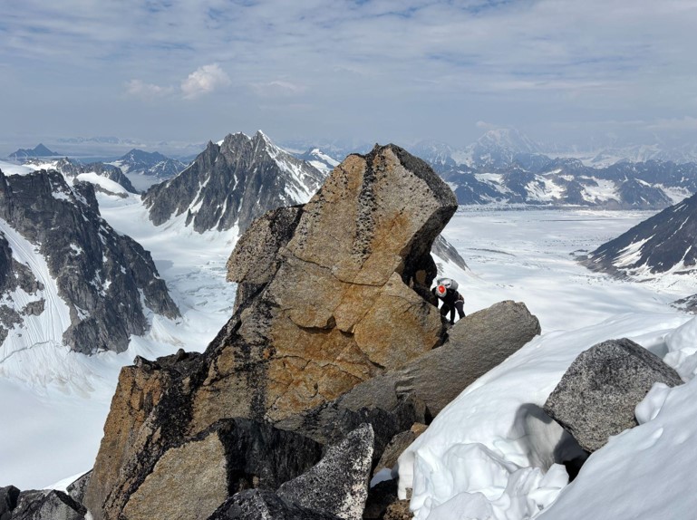 block to navigate along the final ridge Ranger climbs a rocky outcrop with the mountain range in the distance