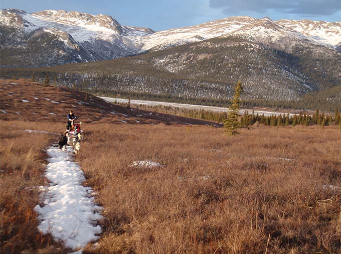 brown landscape, devoid of snow but for a single trail leading toward mountains