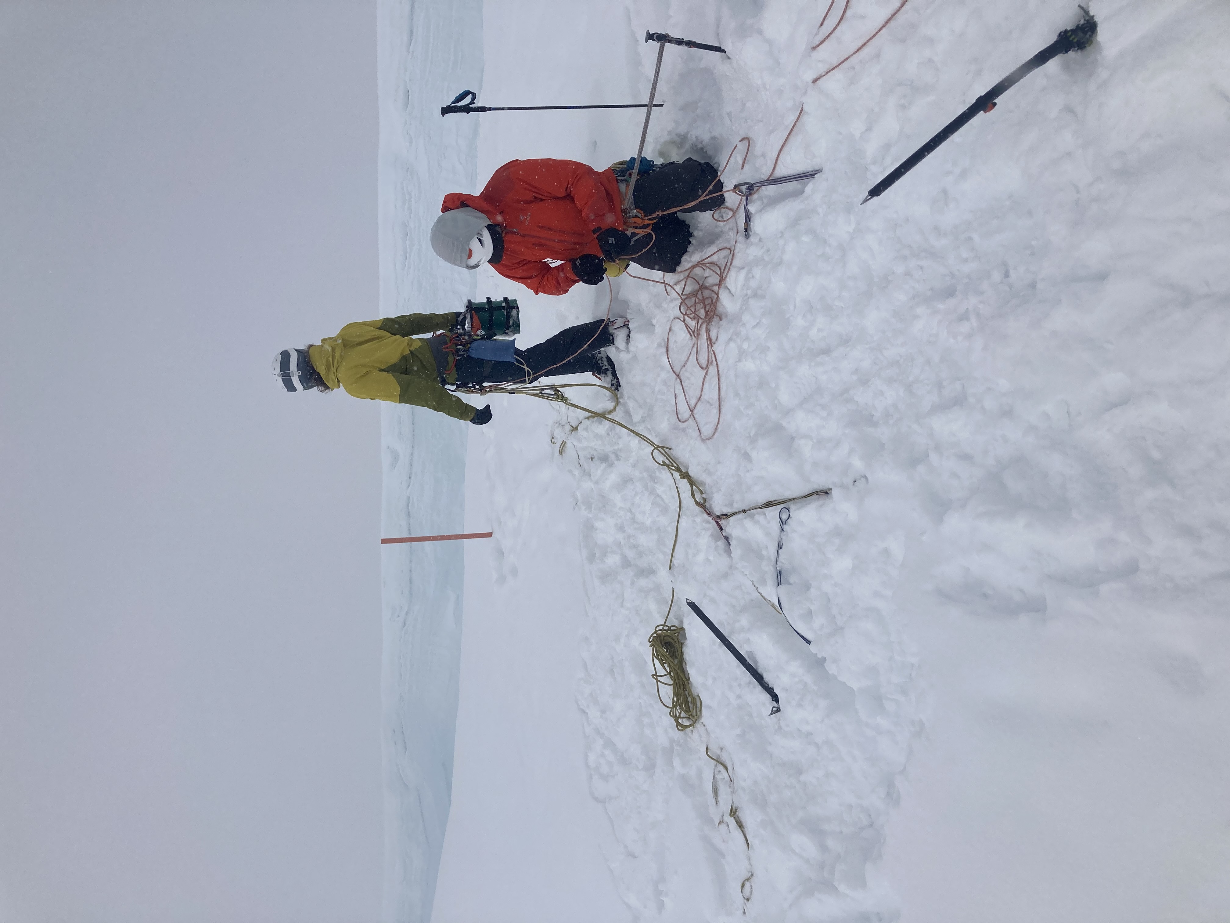 clean-up Two climbers rig up a rope system near the edge of a crevasse
