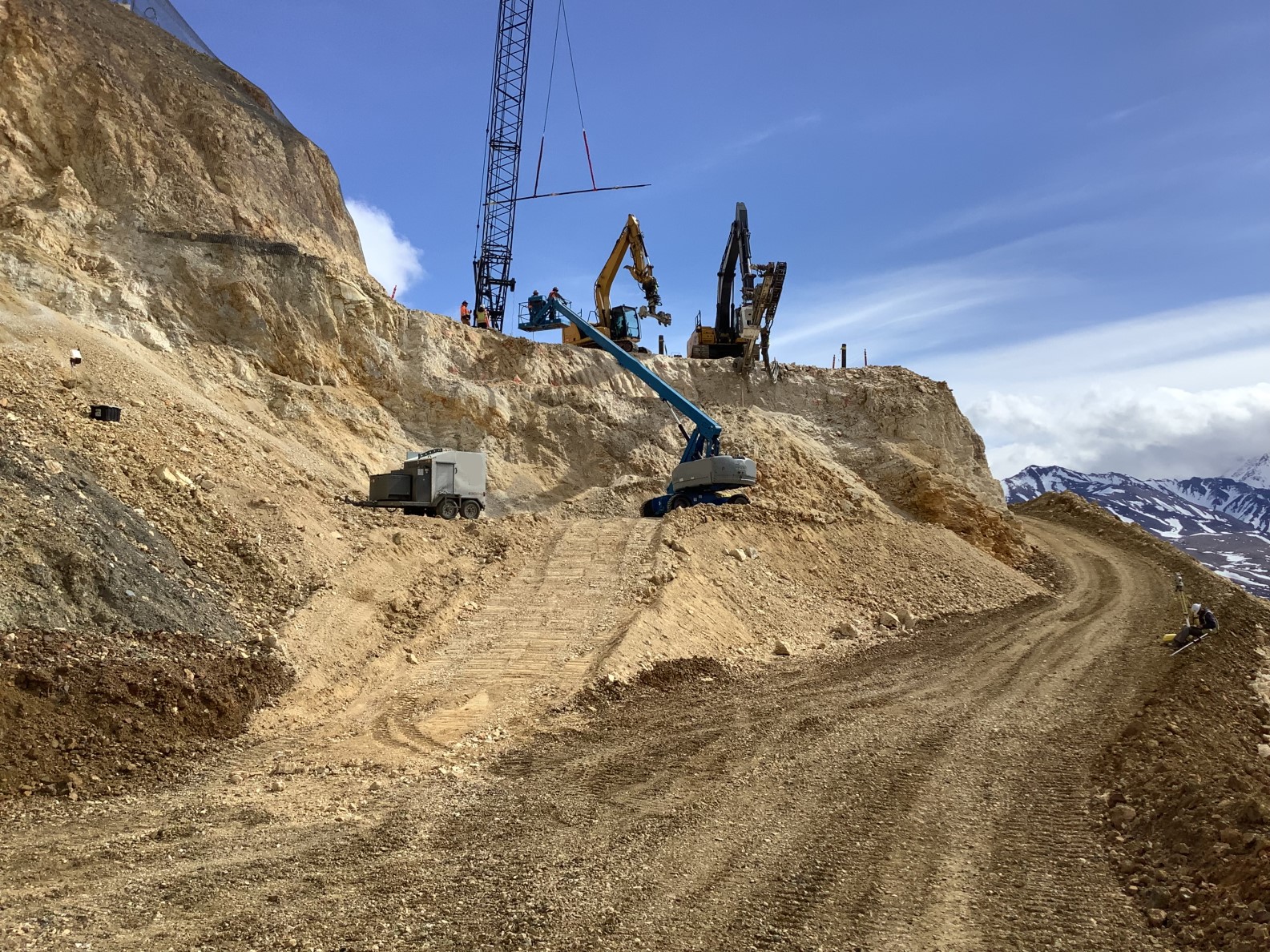 Several workers and pieces of heavy machinery on the east abutment of the landslide.