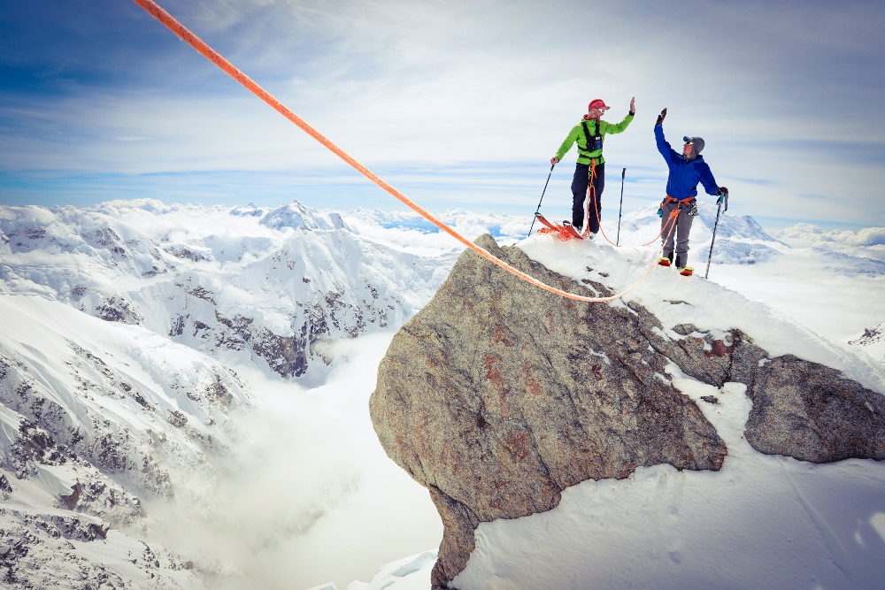 Two roped mountaineers give each other a high five