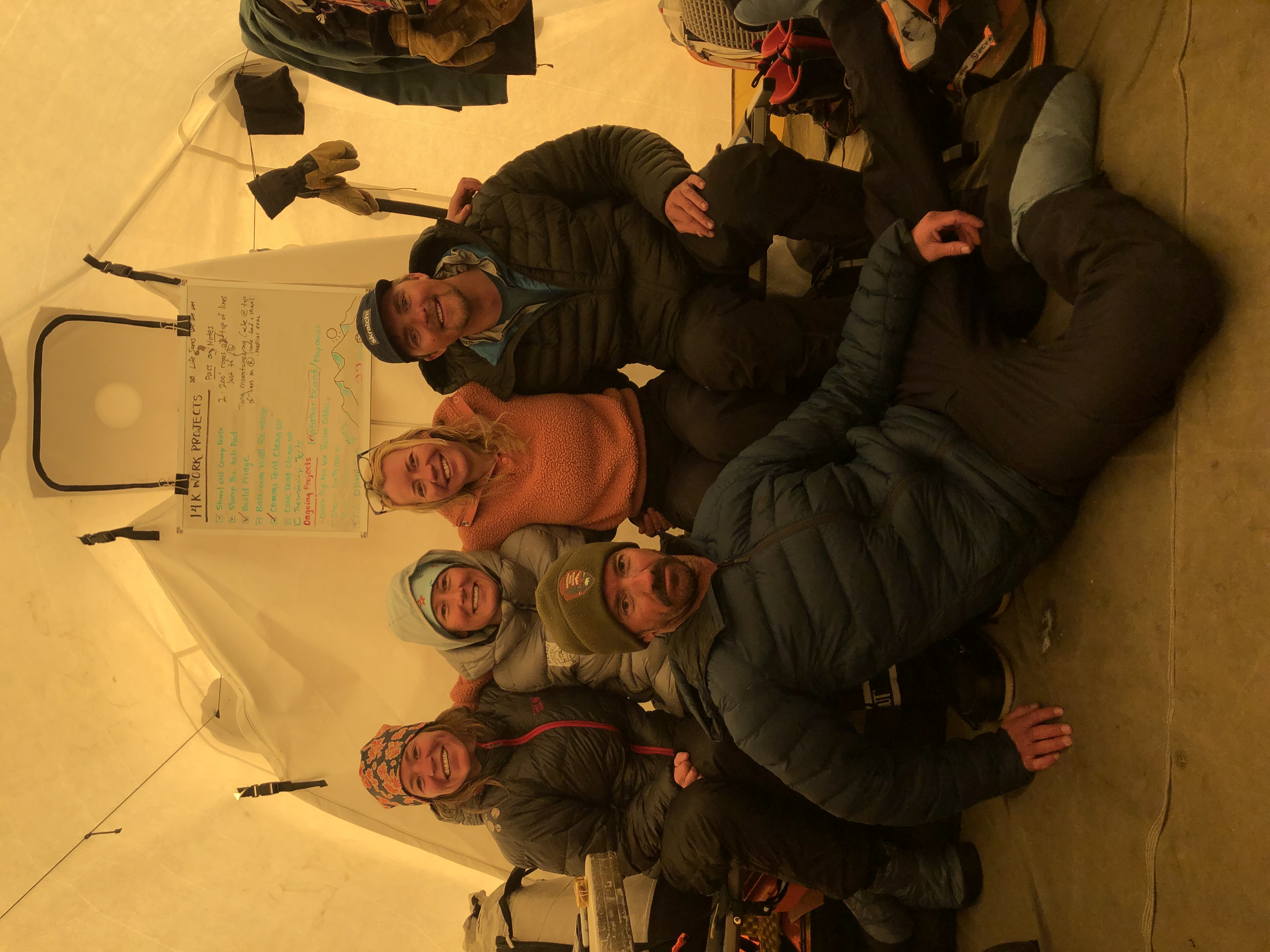 Four rangers sit on a cot in a yellow tent, with one ranger lounging at their feet