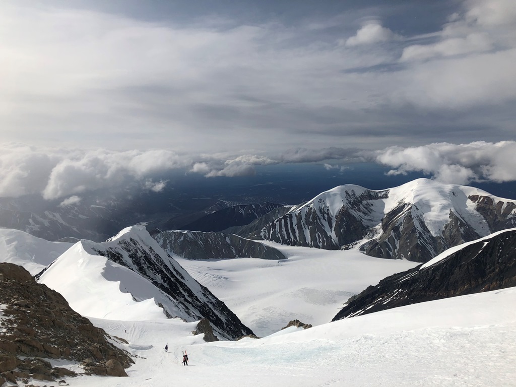 Two climbers descend a snowfield between rocky ridges