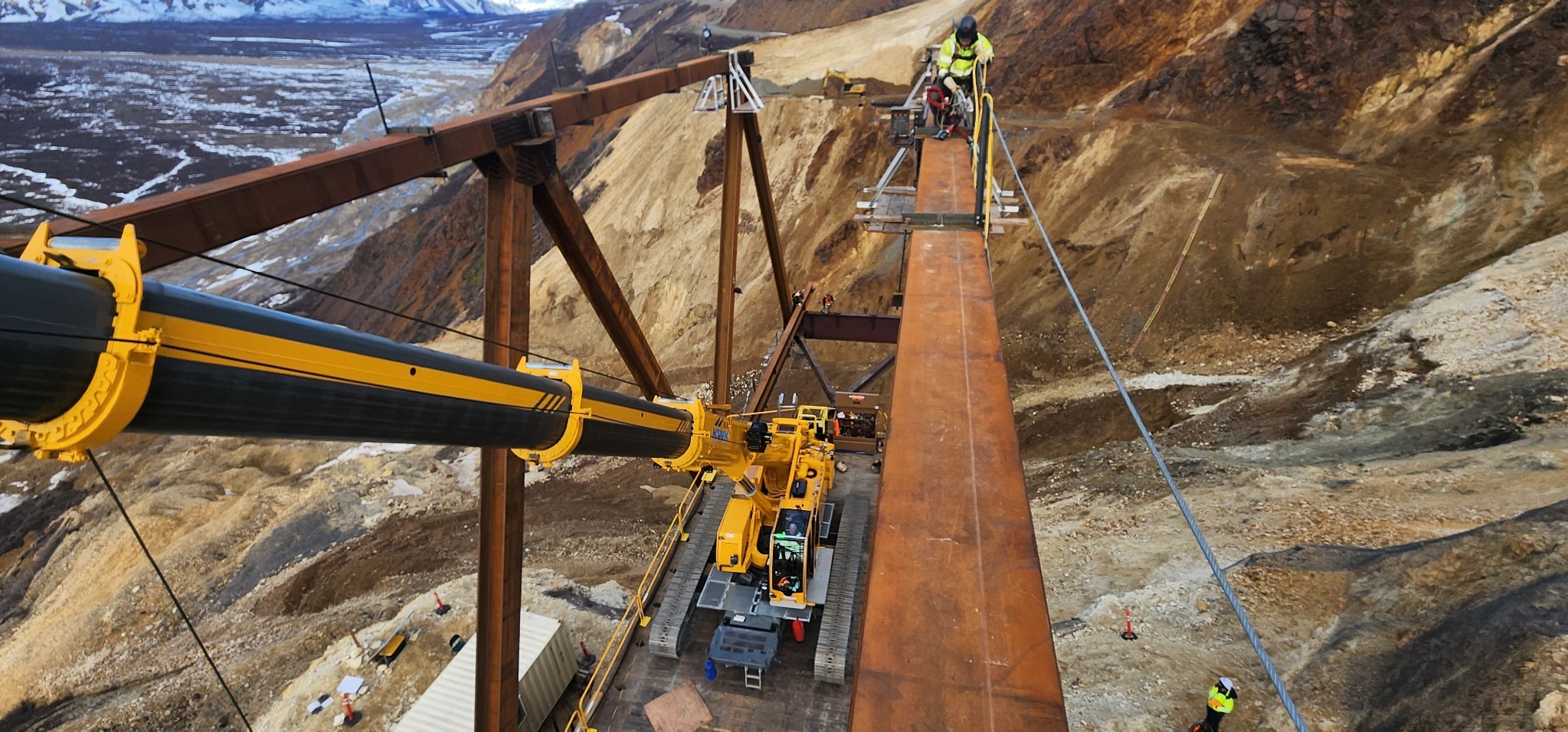preparing to torque verify upper connection to U5 bolts proHNS A worker with tools on top of a metal beam that makes up part of the top of the bridge. A crane sits on the bridge below.