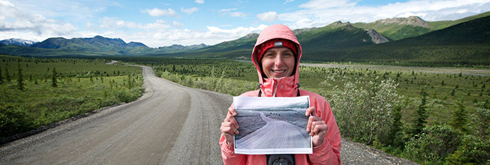 a teacher standing on the park road, mountains in the background