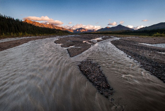 View above a braided river with snow-capped Alaska Range in distance