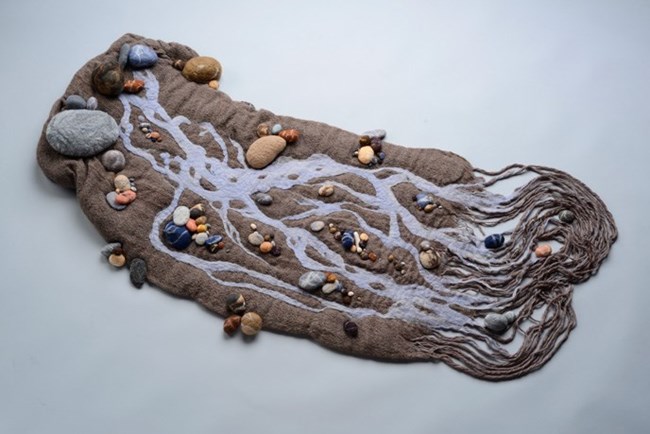 fabric artwork depicting stylized river and rocks