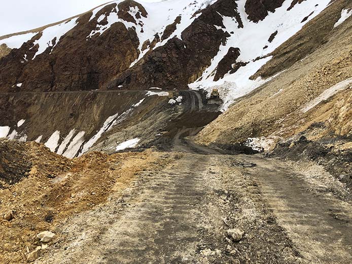 a front end loader on a dirt road on the side of a steep mountain