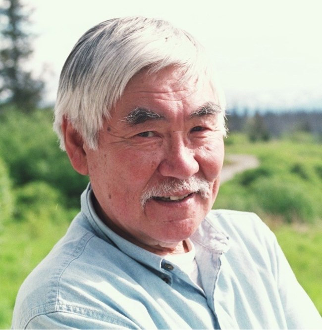 an alaska native man with white hair posing for a photo outdoors