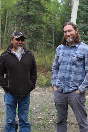 two men posing for a photo outside