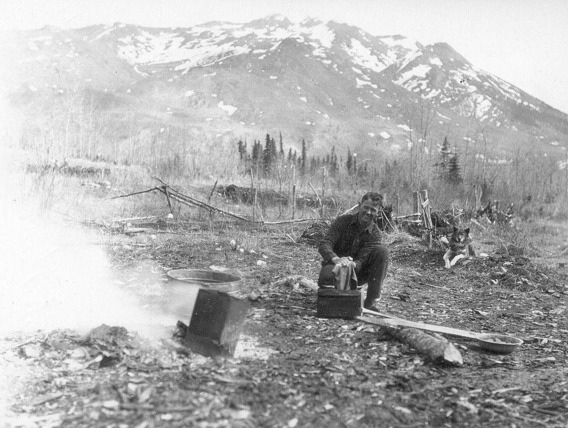 Allman near Riley Creek 1930 historic photo of a man kneeling by a creek