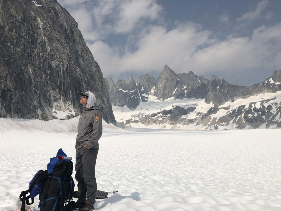 a man standing on a glacier near a steep mountain