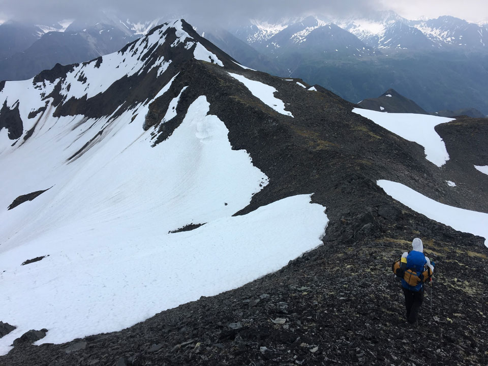 kichatna-2 man hiking down a knife-edge ridge on a mountain