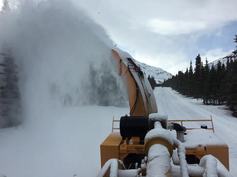 a large piece of equipment blowing snow off a road a large piece of equipment blowing snow off a road
