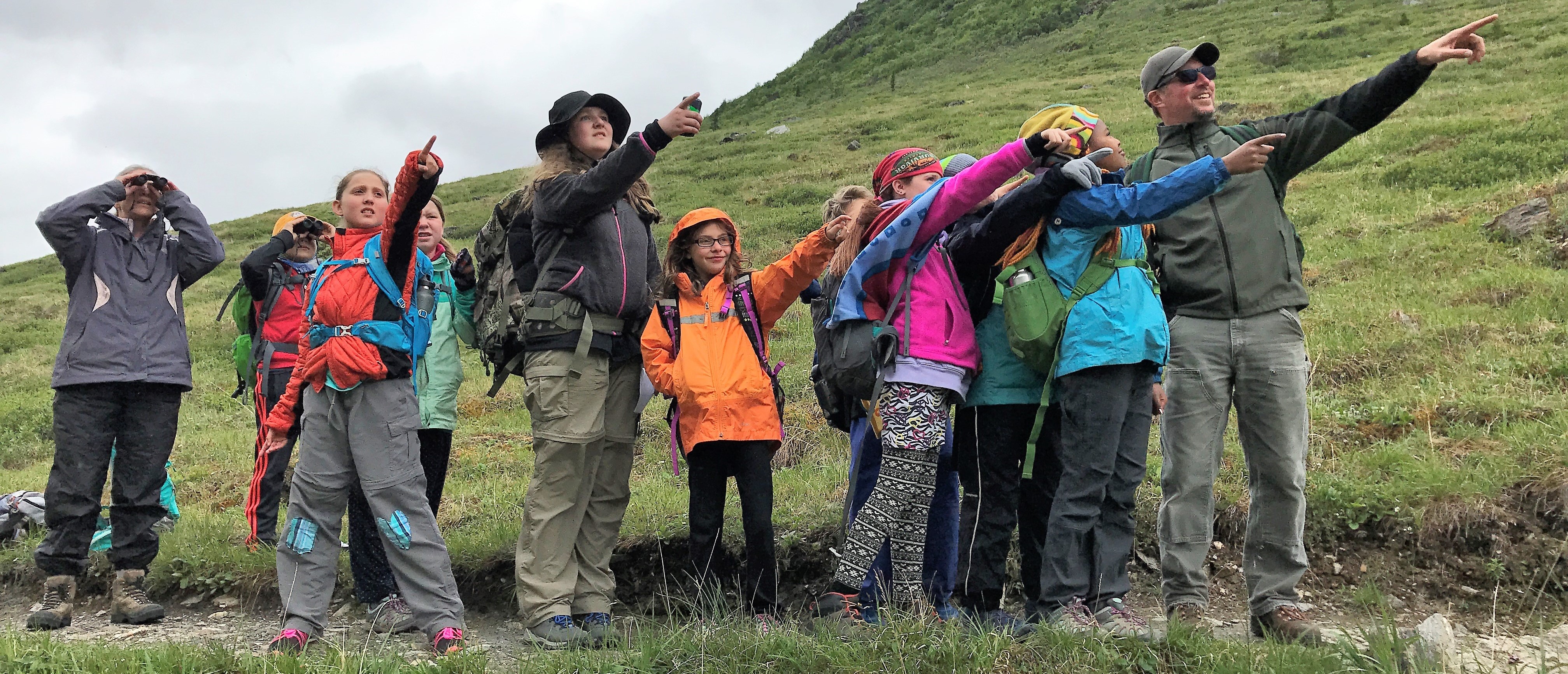 a group of hikers point in the distance