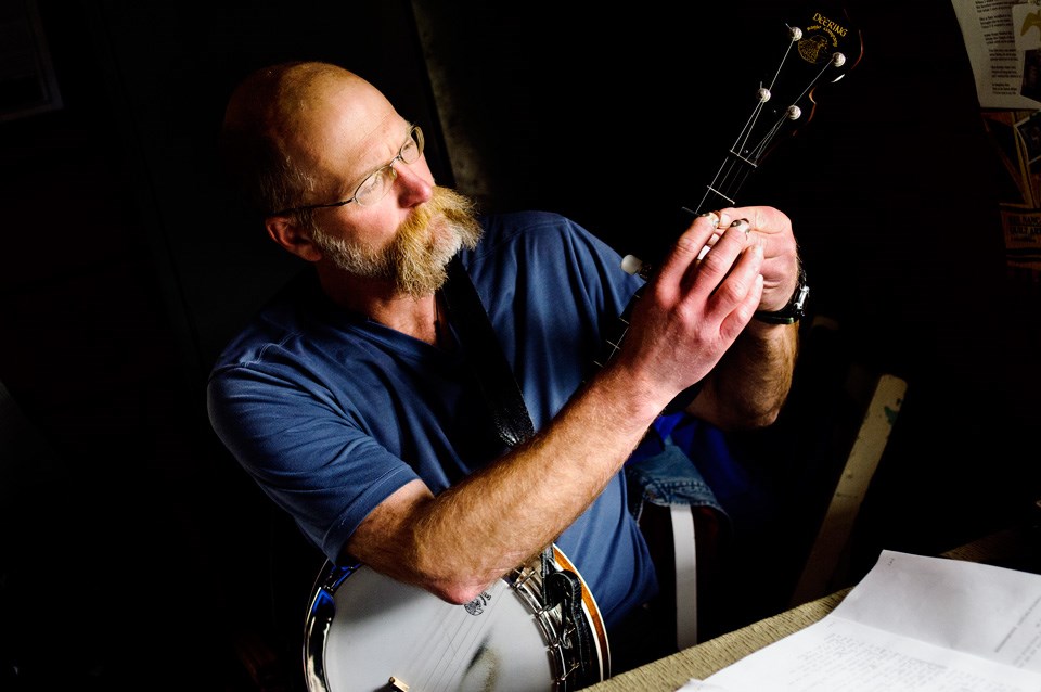 Musician places a capo on the neck of a banjo Musician places a capo on the neck of a banjo