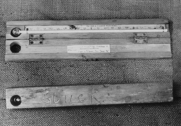 A historic black and white photograph of a wooden thermometer with the name "Stuck"
carved into it.