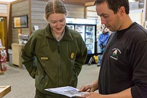 Uniformed ranger and firefighter in black t shirt look at a map together