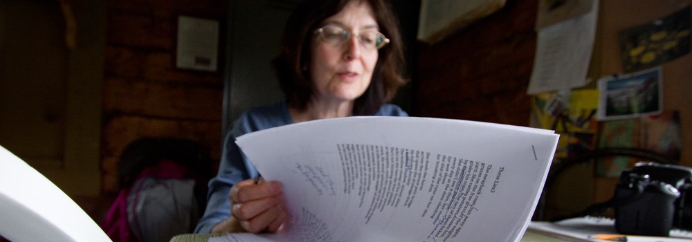 a woman sorts through a stack of papers on a desk