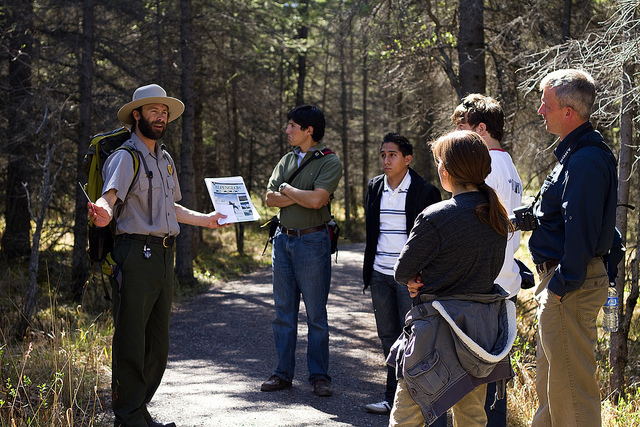 a ranger speaking to a group of people on a forested trail